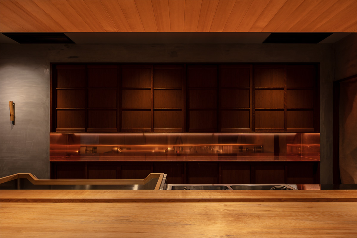 日本料理店「近野」のバックカウンター。チェリー材の収納と銅板が調和した上質な内装。