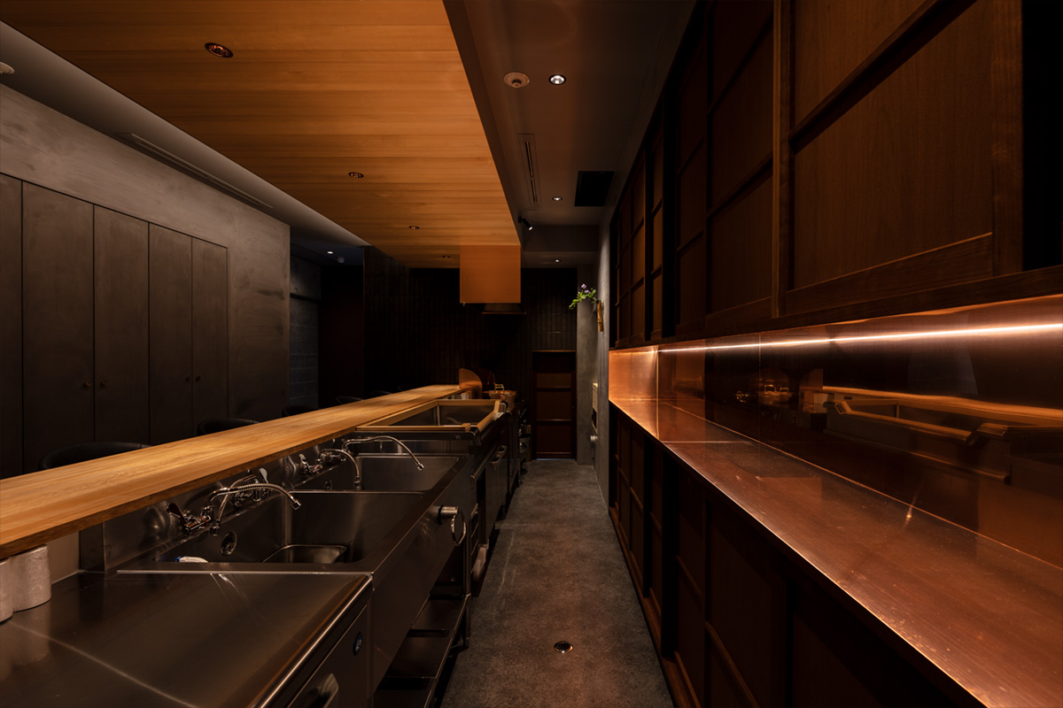 日本料理店「近野」の厨房設備。ステンレスシンクと木天井が融合した京都の和モダン店舗デザイン。