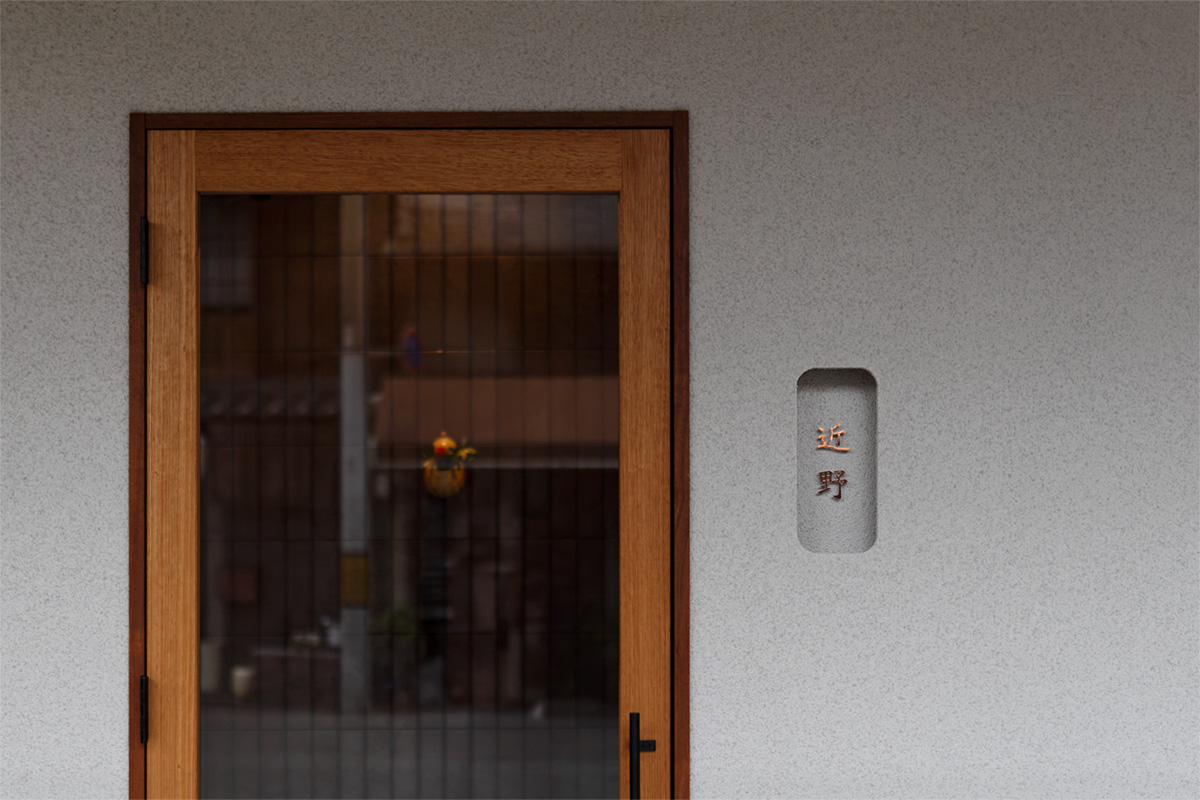 京都市東山区の日本料理店「近野」外観。木枠扉、控えめな銅サインが特徴の静かなエントランス。京都市東山区
