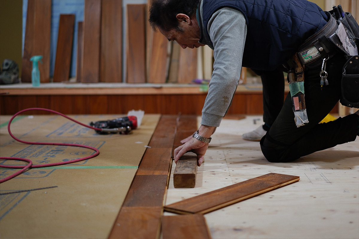 大工さんが丁寧に無垢フローリングを貼っています