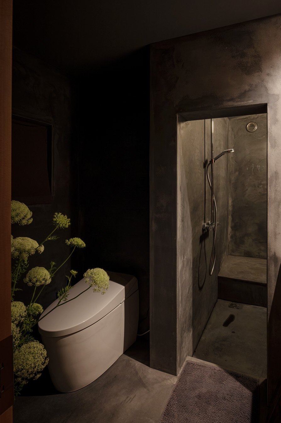 「Badu」の化粧室。モルタル壁とグリーンが調和するミニマルで上質なデザイン。