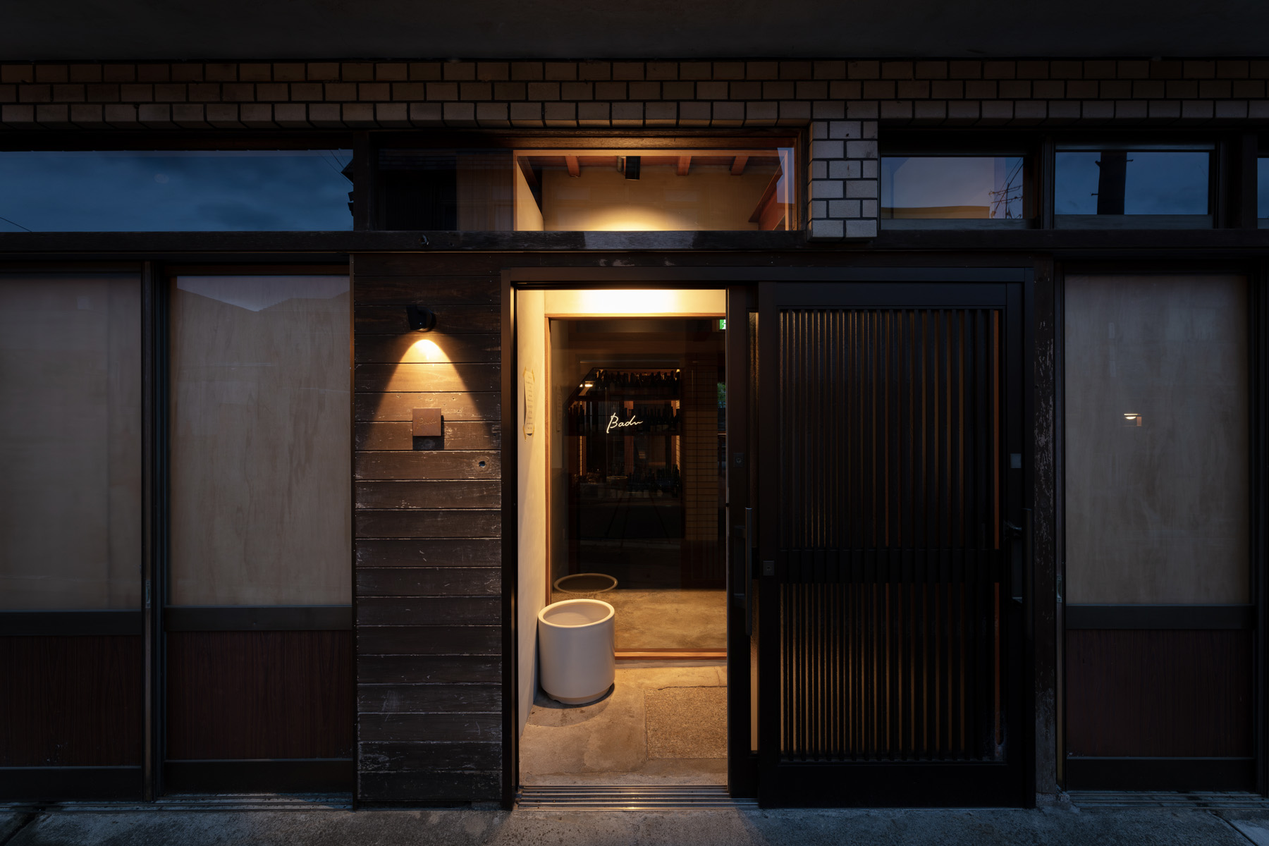 京都の町家を改装したレストランBaduの外観。木とレンガのファサードに柔らかな灯りがともる。柳原照弘氏のデザイン監修のもと洛（RAKU）が施工を担当。
