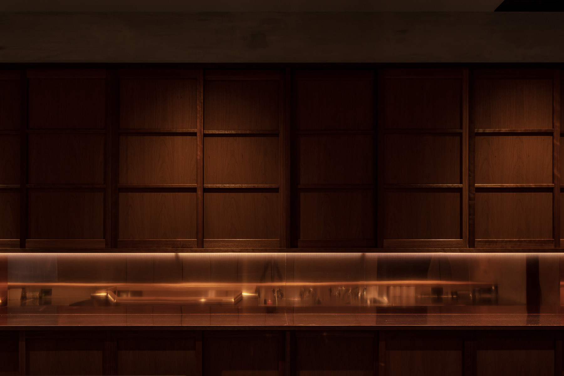 日本料理店カウンター背面。木と銅板を組み合わせた背面収納デザイン。