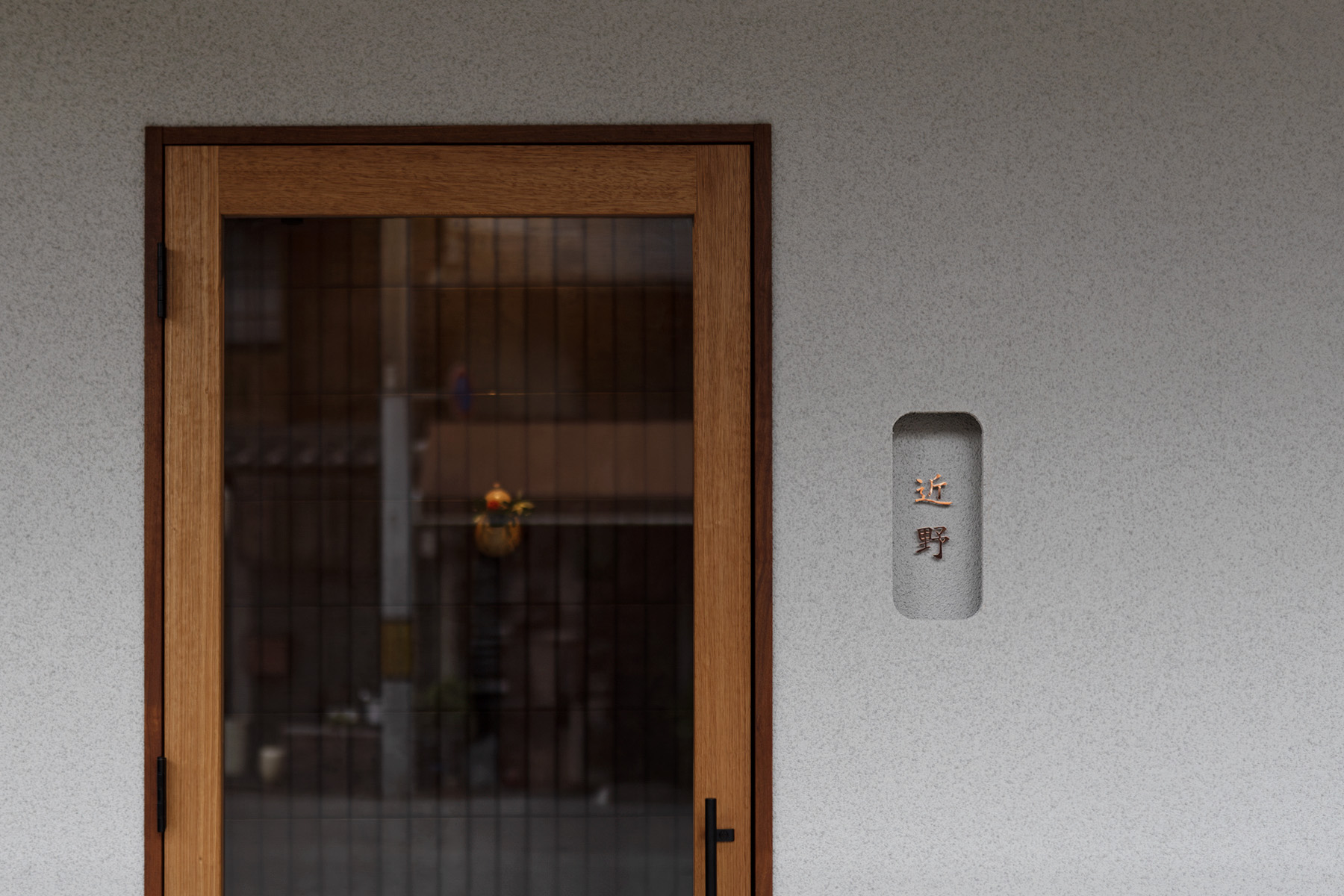 京都市東山区の日本料理店「近野」の外観。木製ドアに銅文字の看板を組み合わせたシンプルなファサード